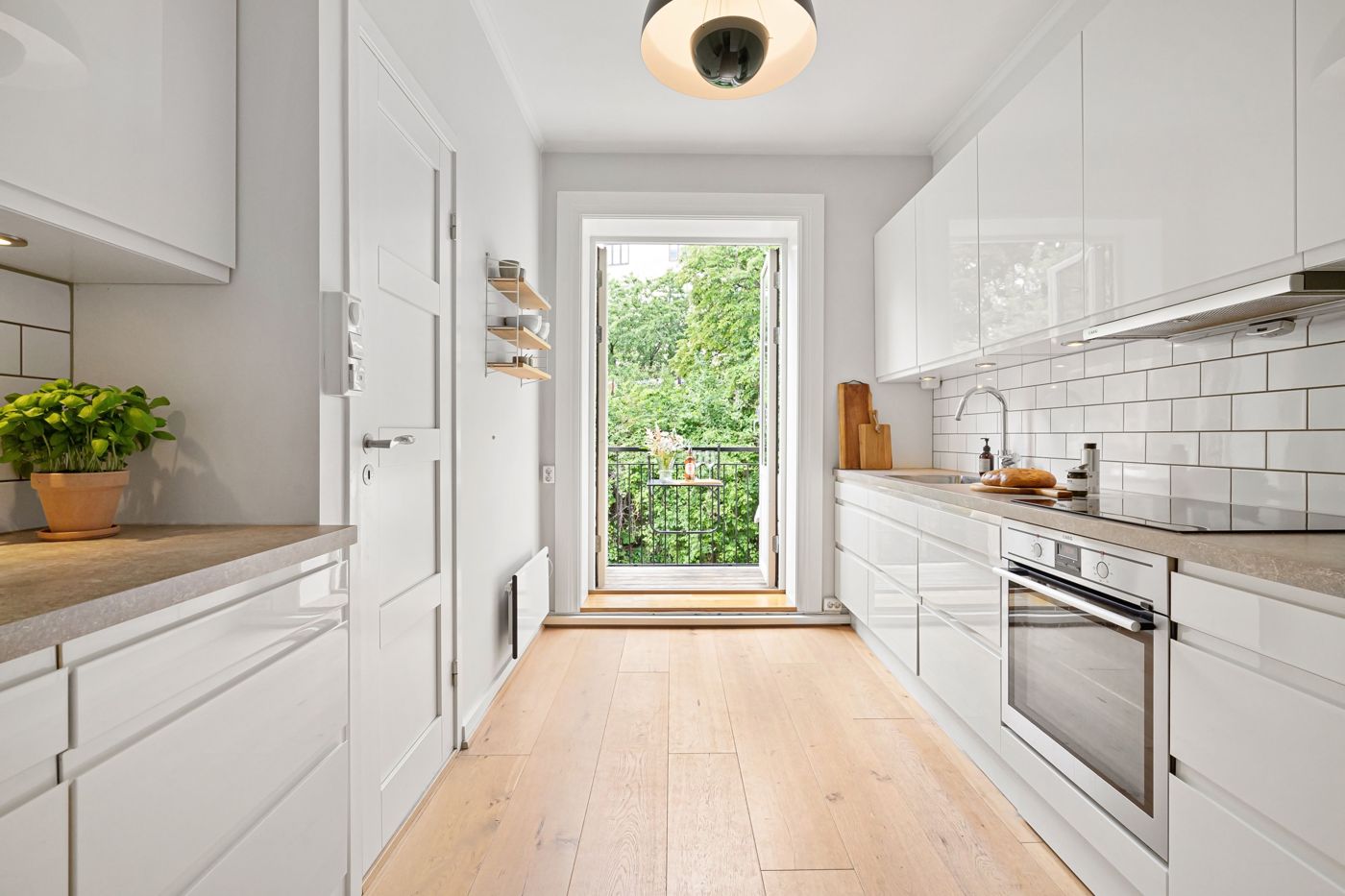 Helle, kompakte Küche mit Balkon und frischen Kräutern